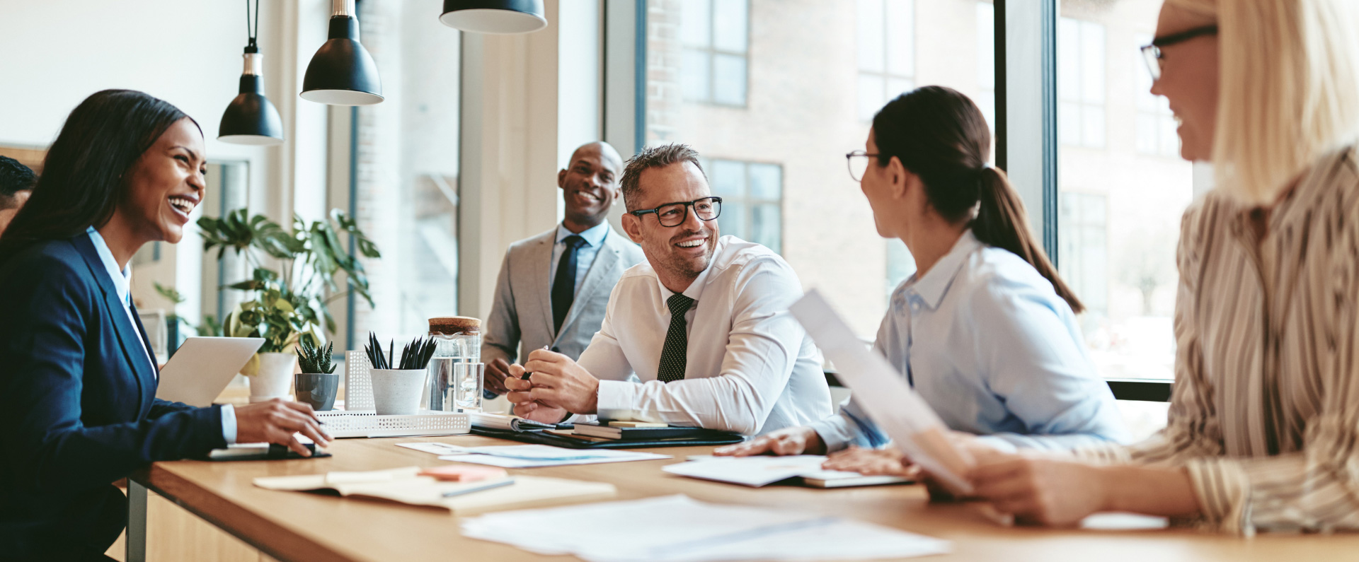 Addison group's employer page, featuring 5 coworkers sitting around a table smiling.