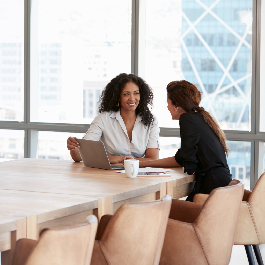 Addison Group candidates page featuring two women coworkers talking at a table with a laptop open