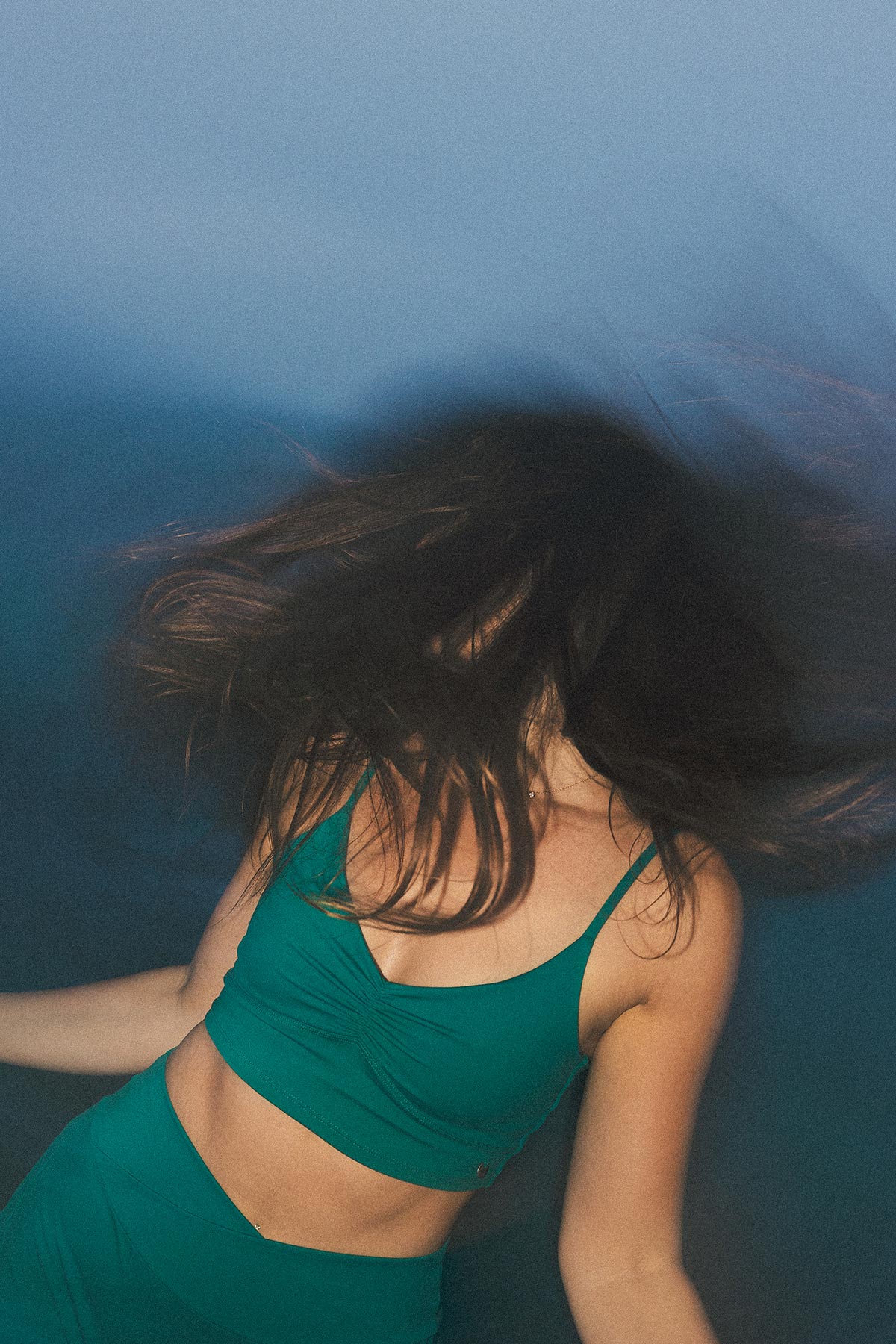Model wearing Ayla Crop in deepsea color against a blue background
